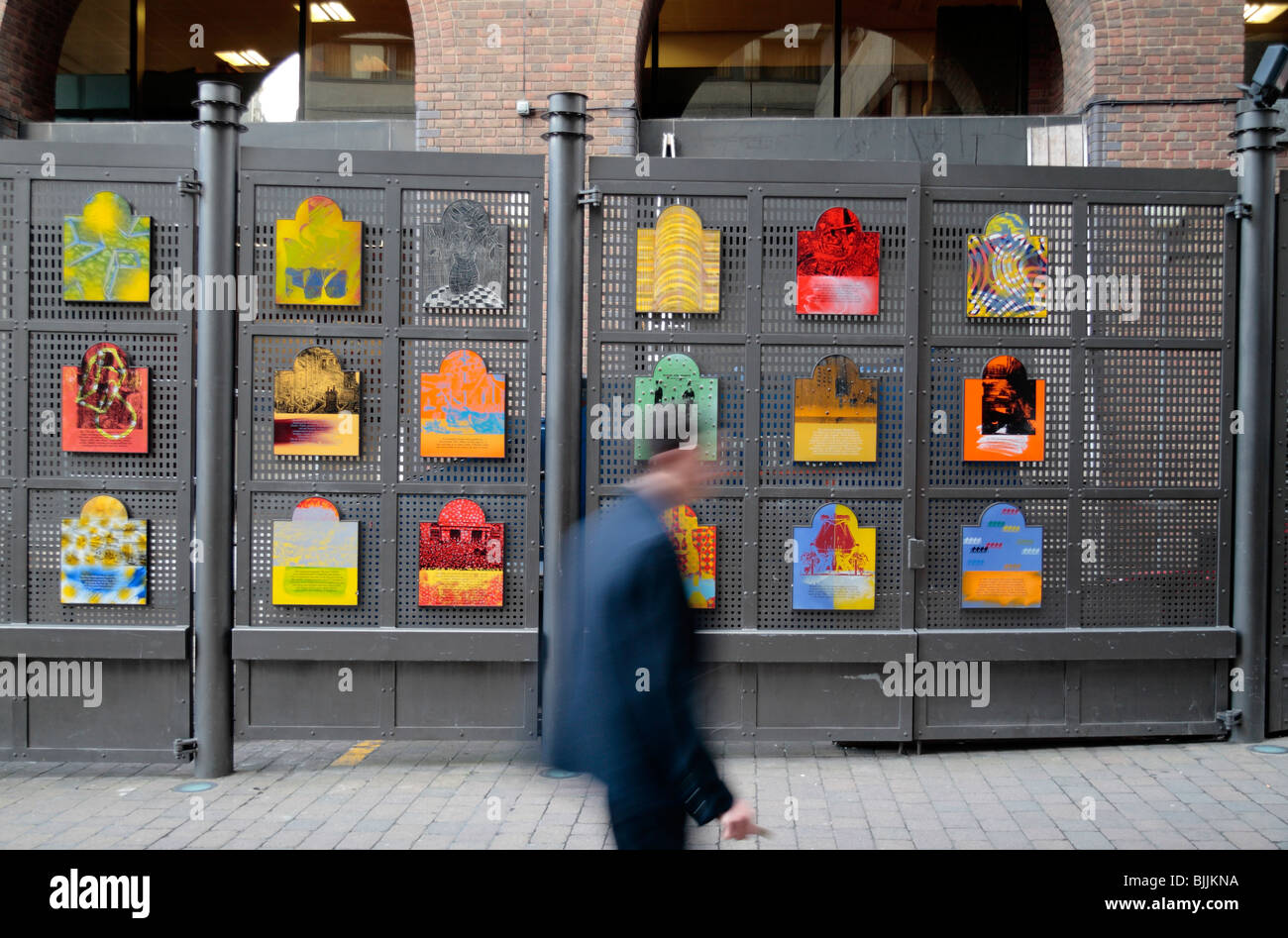 A man walking past a collection of colourful information plaques/art by  Dale Devereux Barker, St Katherine's Dock, London, UK. Stock Photo