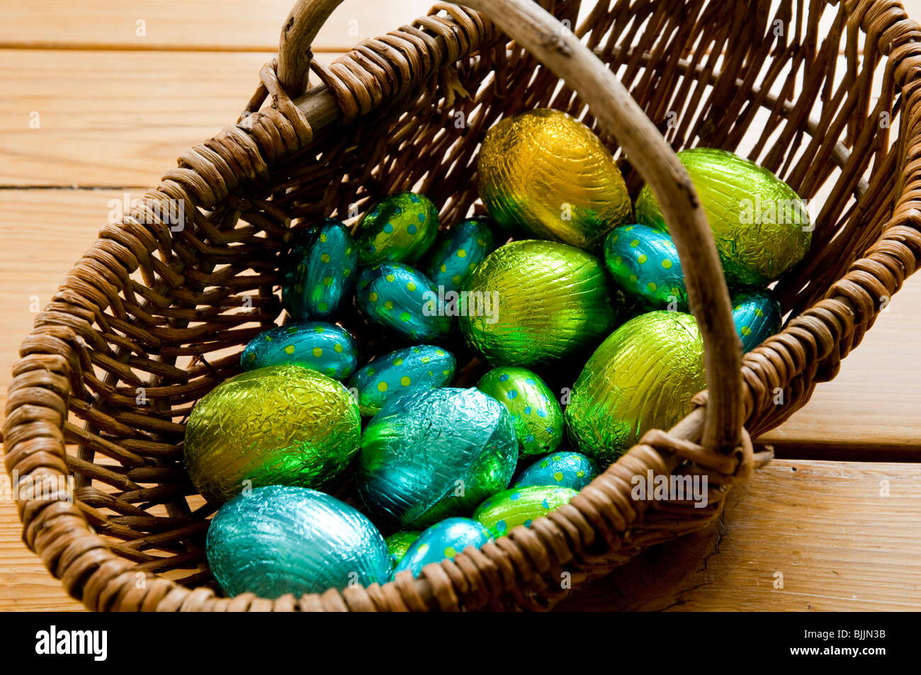A willow basket containing a selection of foil wrapped chocolate easter eggs. Stock Photo