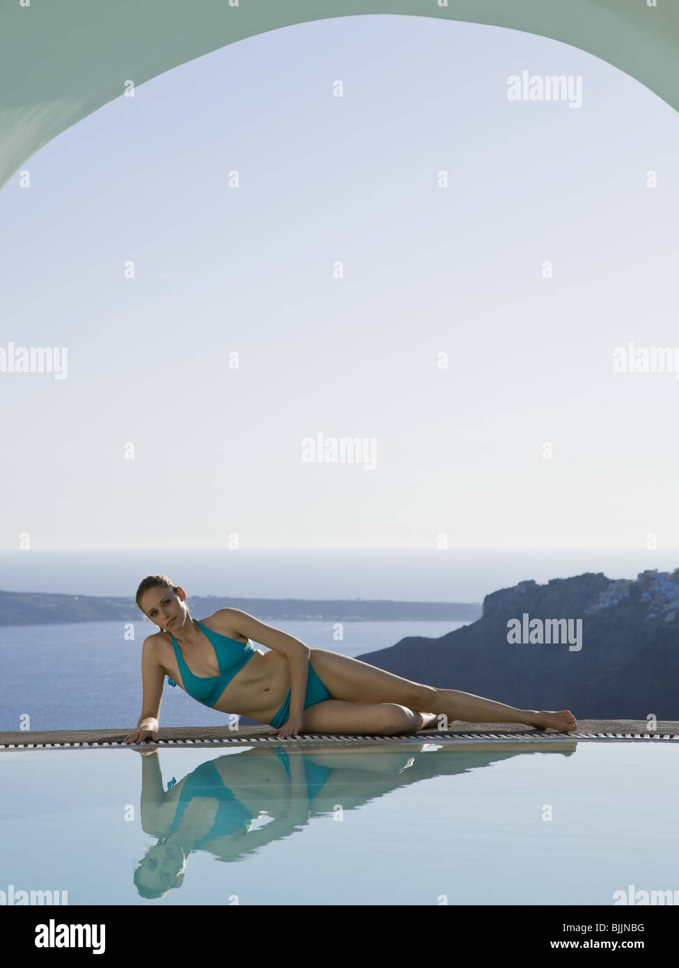 Woman reclining by infinity pool outdoors Stock Photo