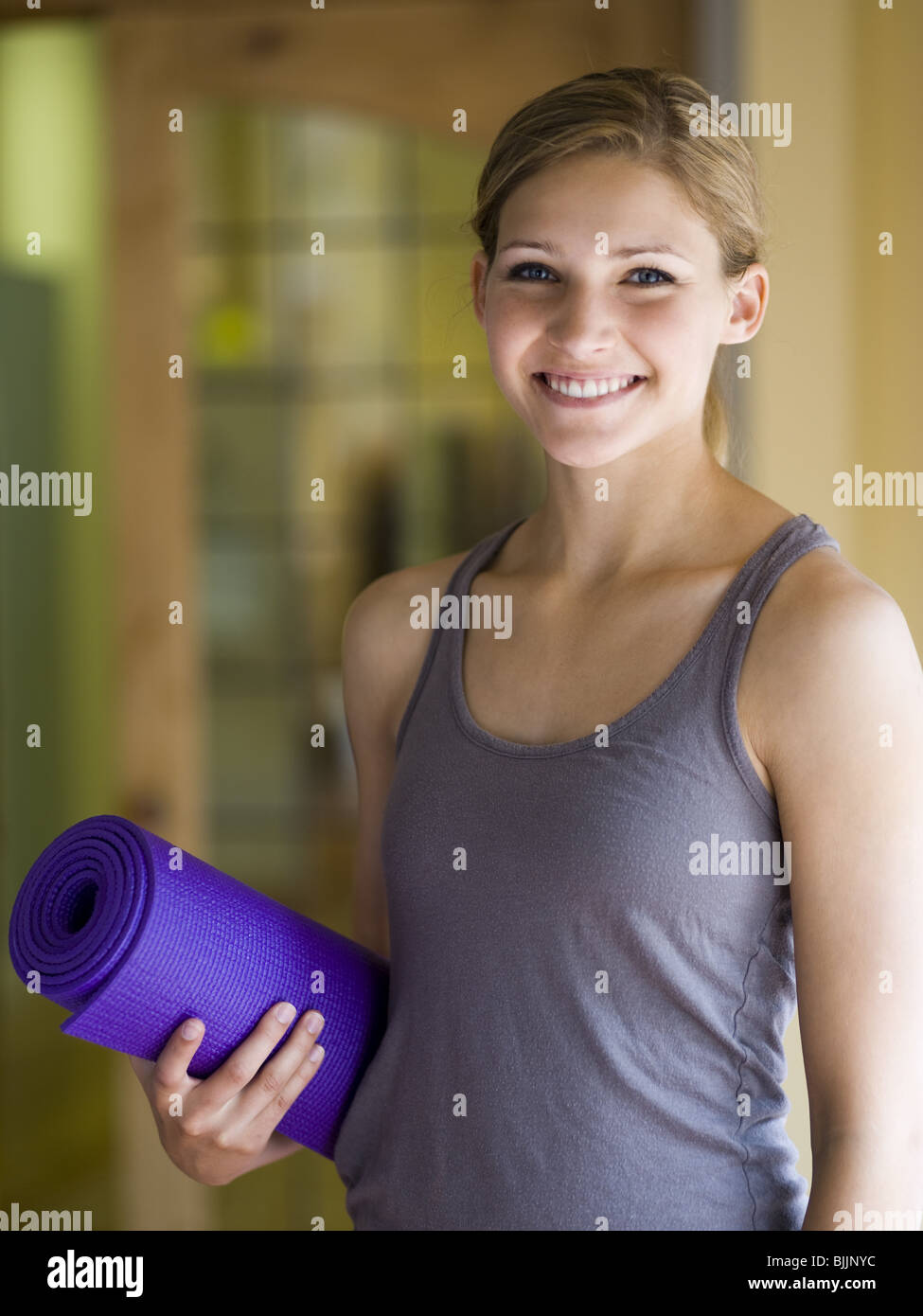 Woman with yoga mat smiling Stock Photo Alamy