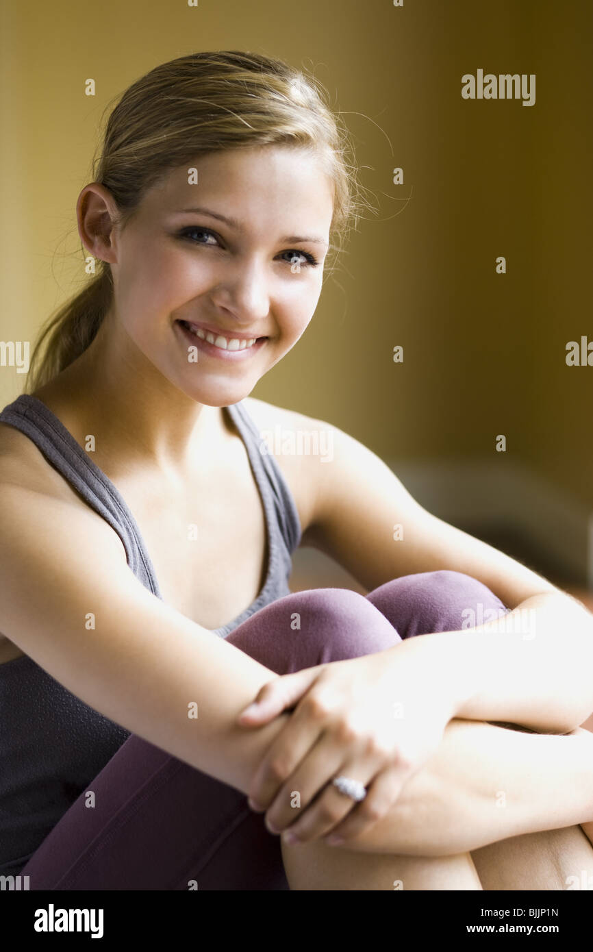 Woman sitting and smiling with arms around knees Stock Photo Alamy