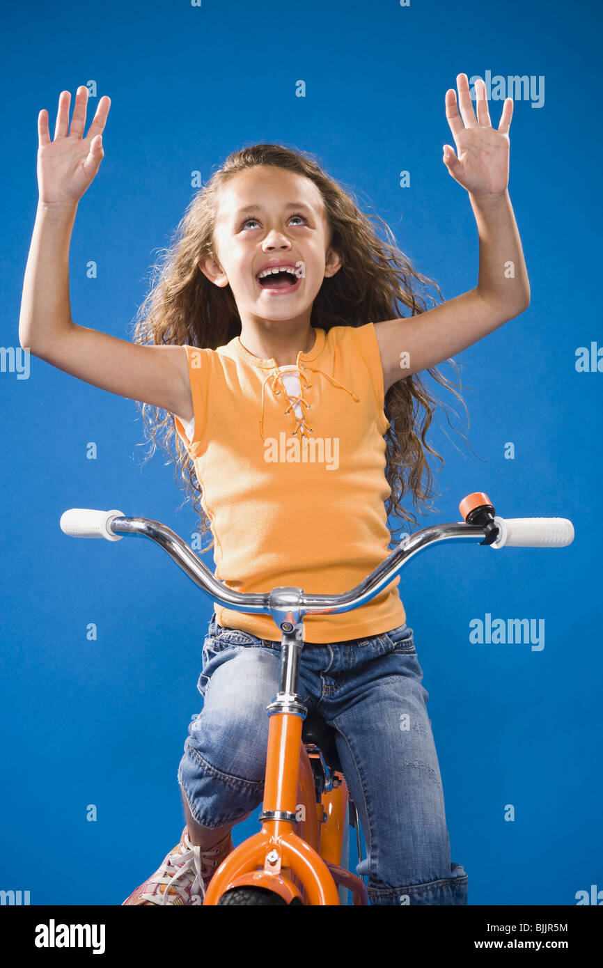 Girl riding orange bicycle with no hands laughing Stock Photo Alamy