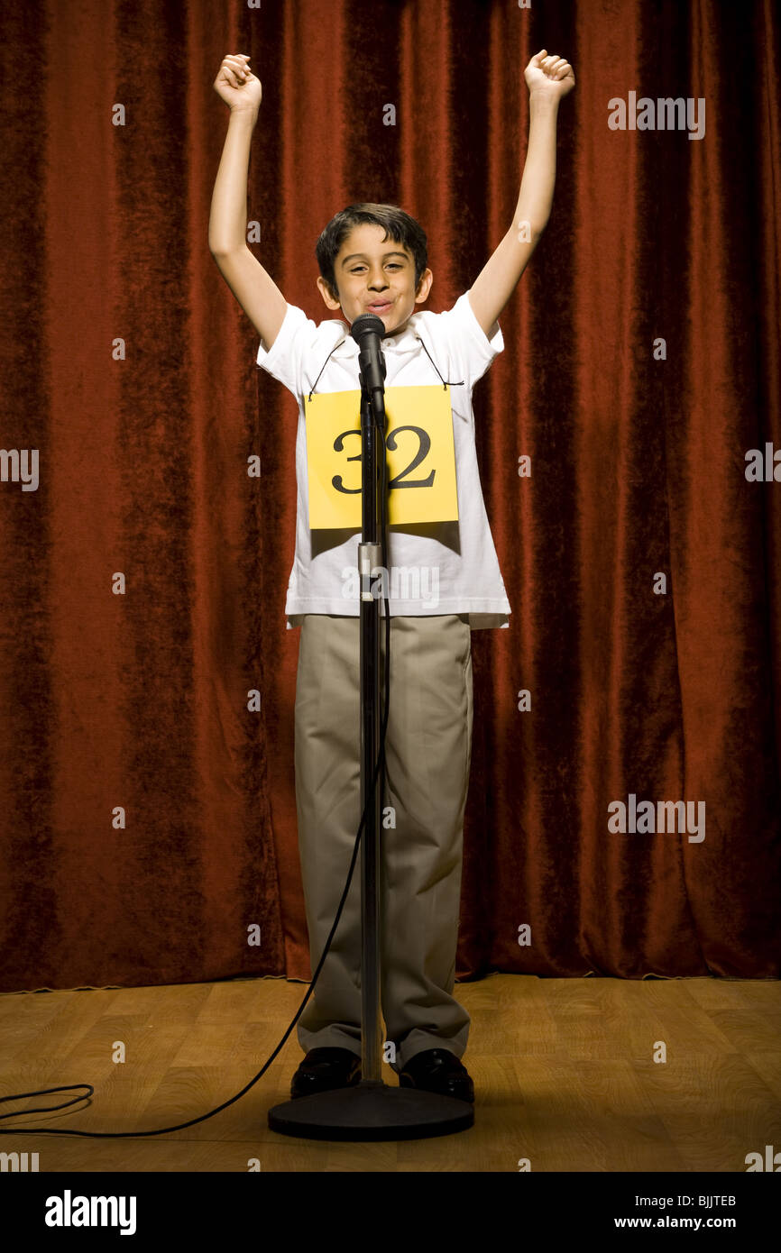 Boy contestant standing at microphone waving and smiling Stock Photo