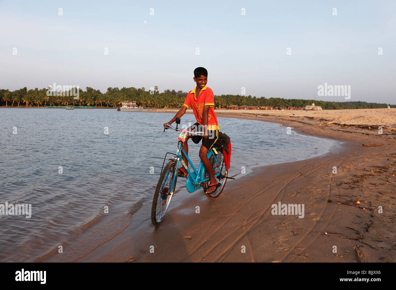 Proud boy riding a bike along the Poovar River, backwater, in front of the Hotel Isola di Cocco Resort, Puvar, Kerala, South In Stock Photo