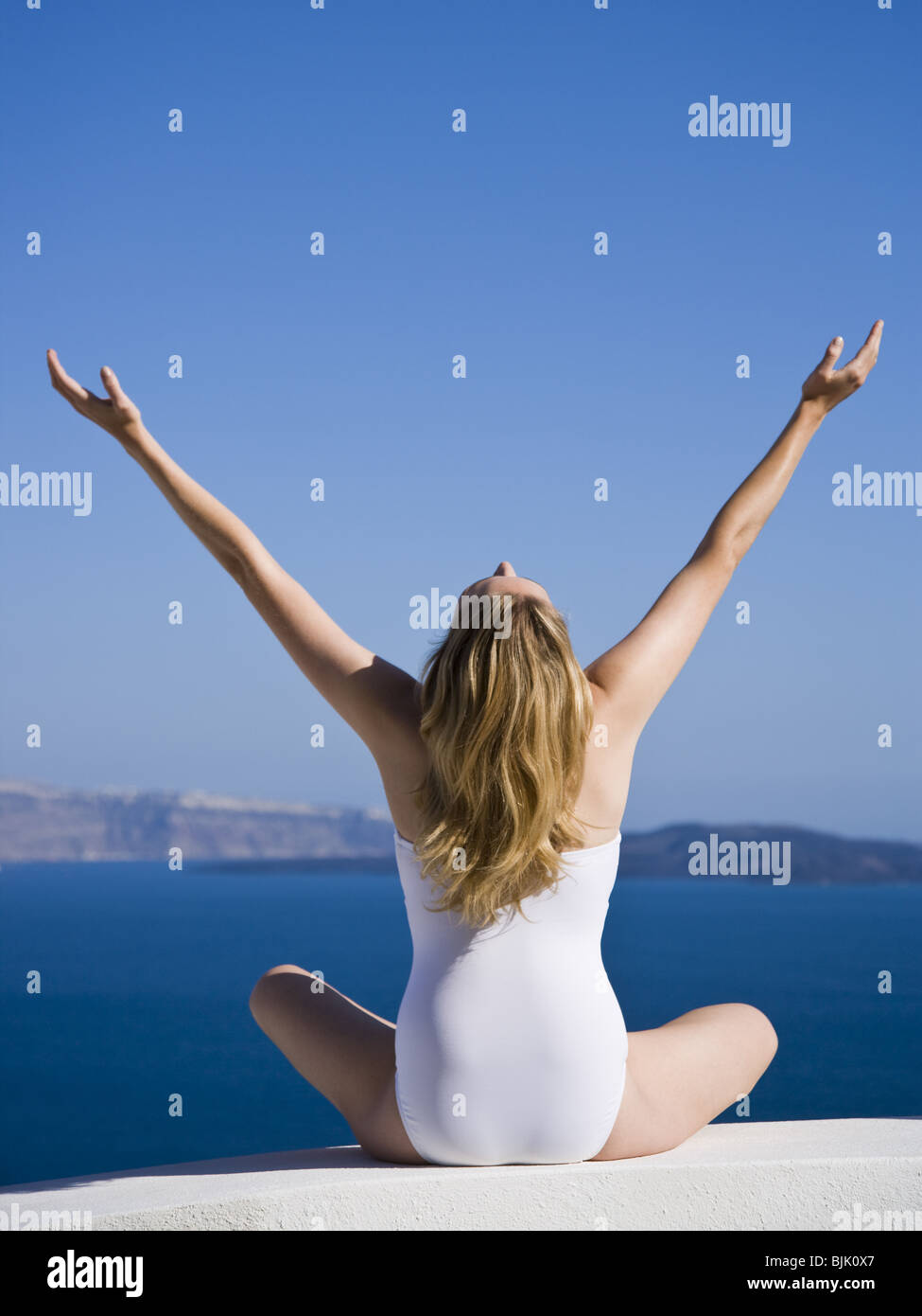 Rear view of woman in swimsuit with arms up Stock Photo