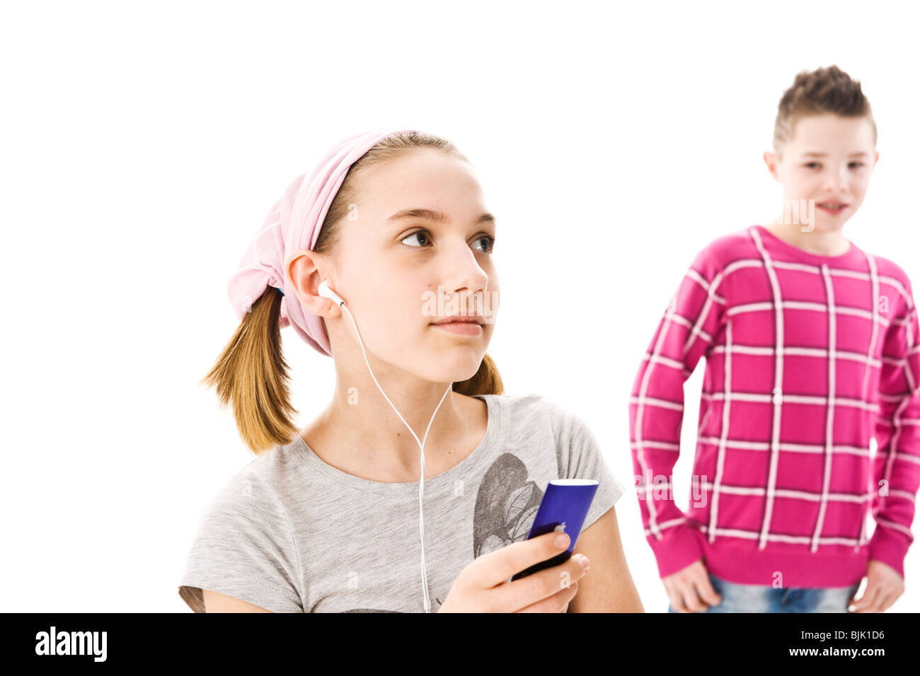 Boy standing behind a girl who is listening to music with headphones Stock Photo