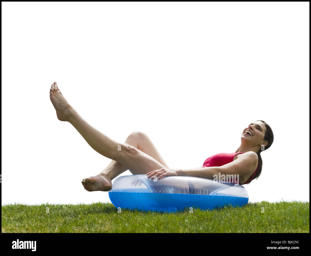 Woman in bikini lying in swimming ring on grass smiling Stock Photo