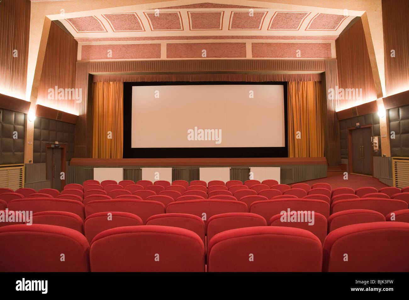 Empty retro cinema auditorium in cubism style with line of chairs and projection screen. Ready for adding your own picture. Stock Photo