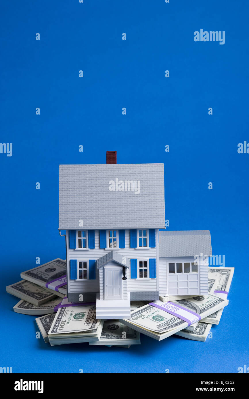 Toy house on pile of one hundred dollar bills Stock Photo