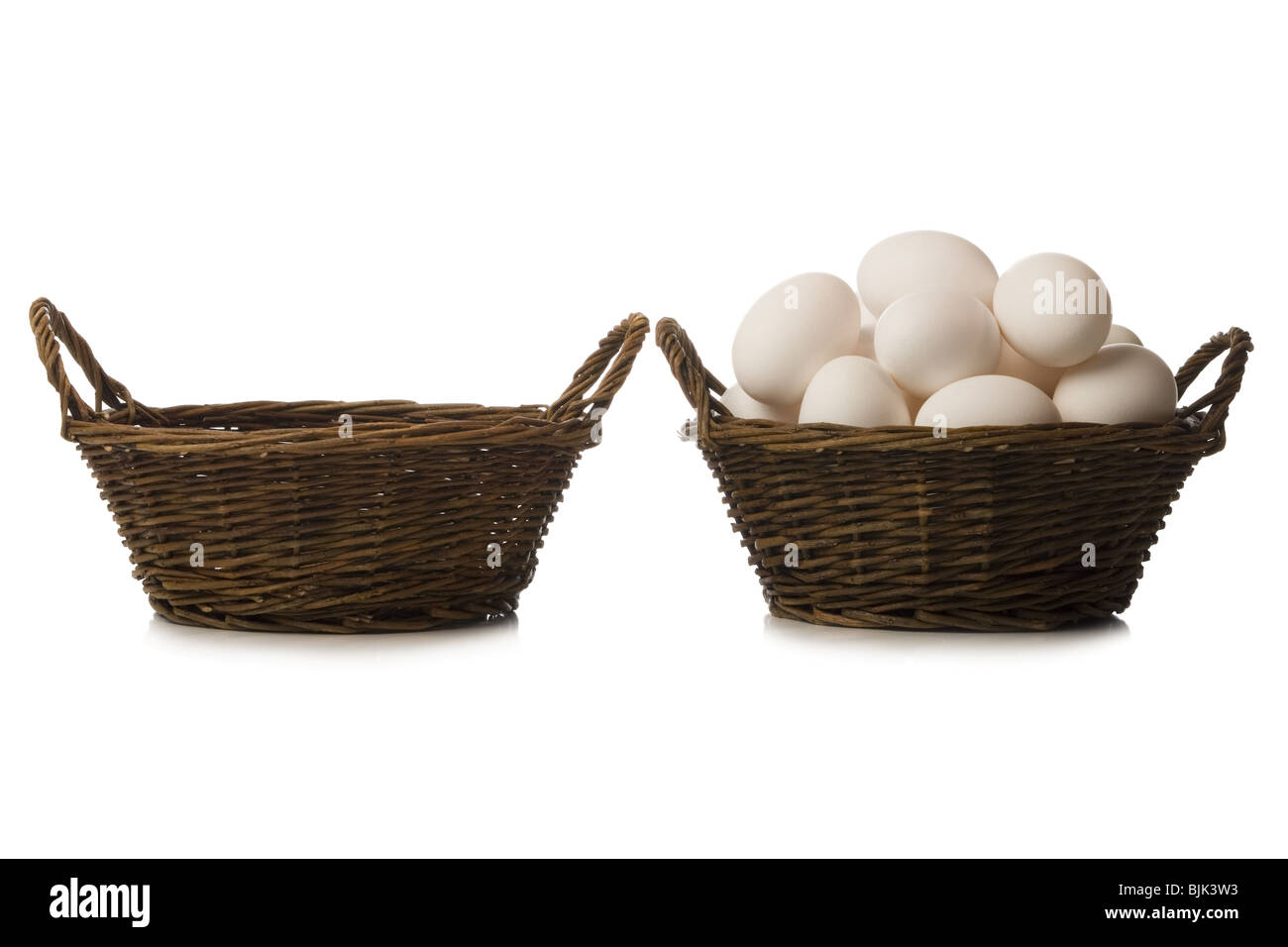 One empty basket and one filled with eggs Stock Photo