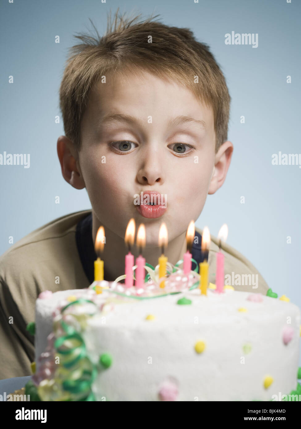 Boy blowing out candles on a birthday cake Stock Photo Alamy