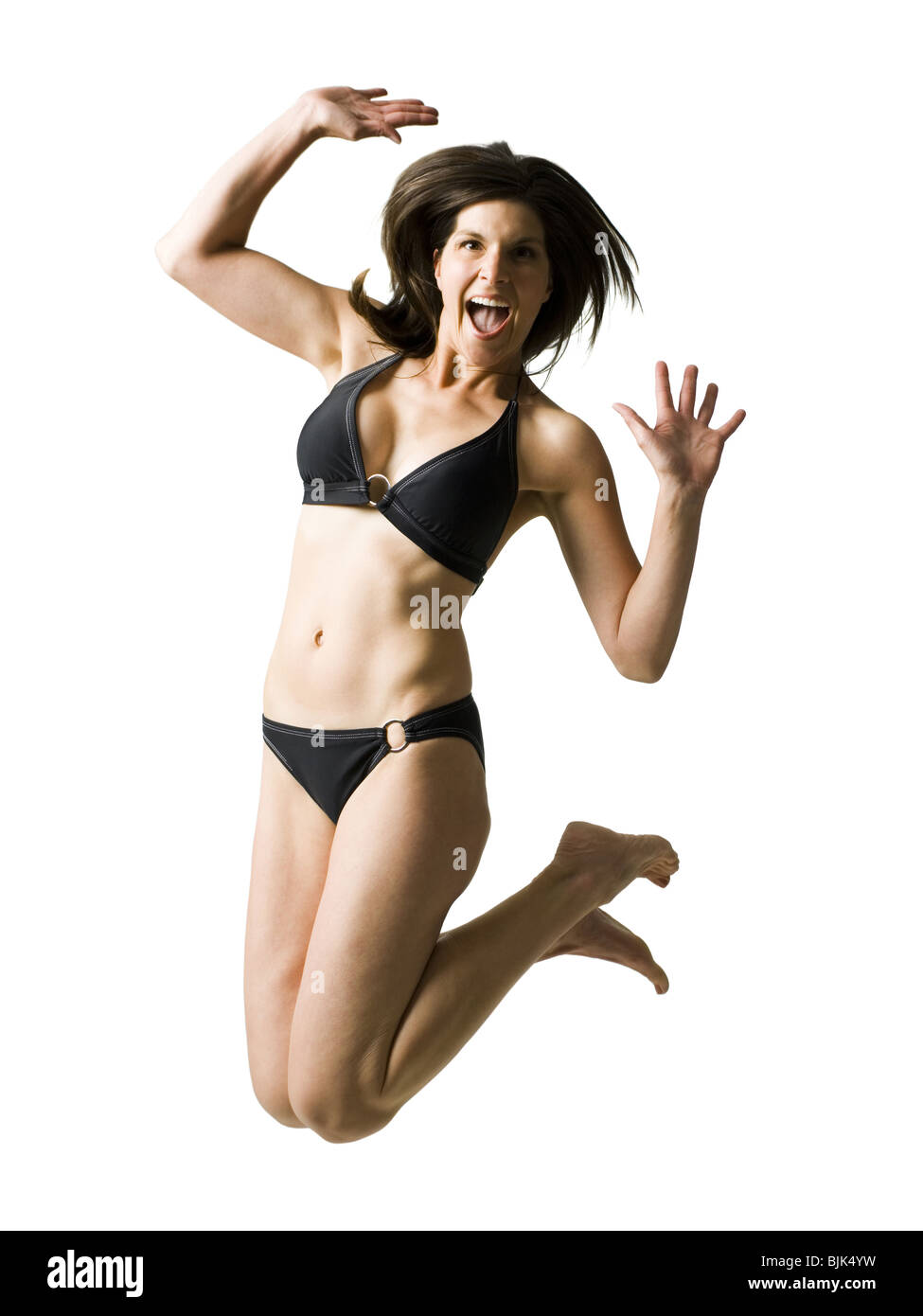 Woman in bikini jumping with hands up smiling Stock Photo