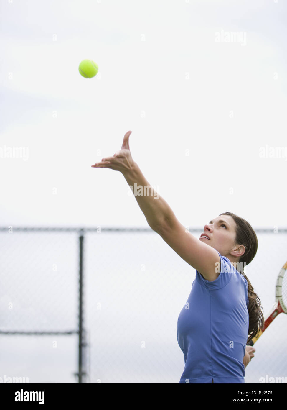 Woman tossing tennis ball in air to serve Stock Photo Alamy