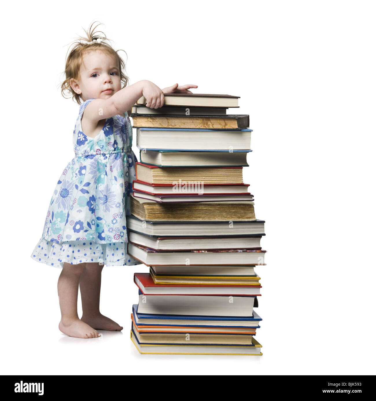 Young girl standing beside pile of hardcover books Stock Photo - Alamy