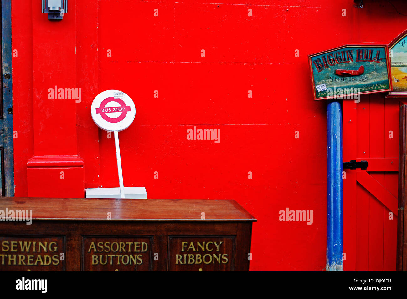 A collection of vintage articles standing outside with a bright red wall behind Stock Photo