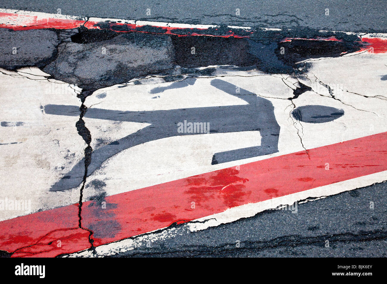 Asphalt cracked by frost and cold with a painted pedestrian crossing sign Stock Photo