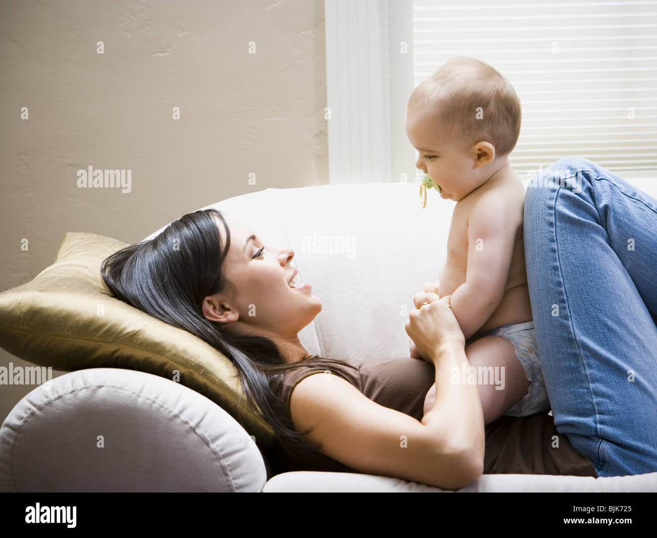 Woman lying down on sofa with baby Stock Photo