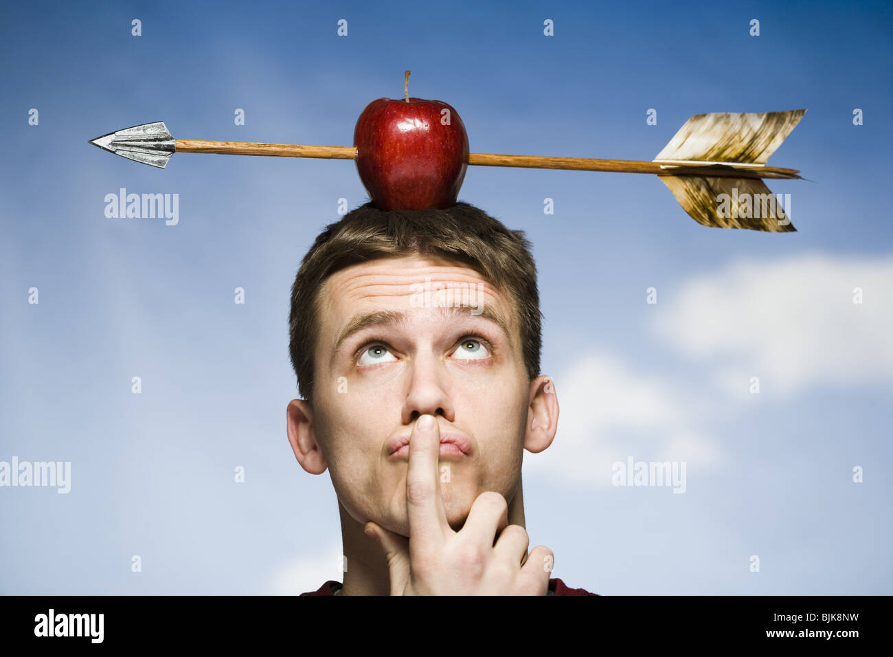 Man outdoors with arrow through red apple on head Stock Photo