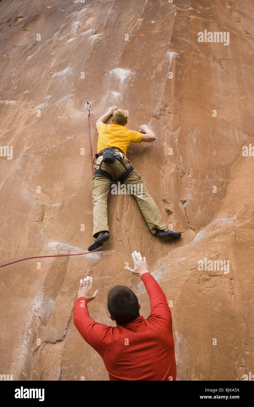 Man with arms raised and man climbing mountain Stock Photo Alamy