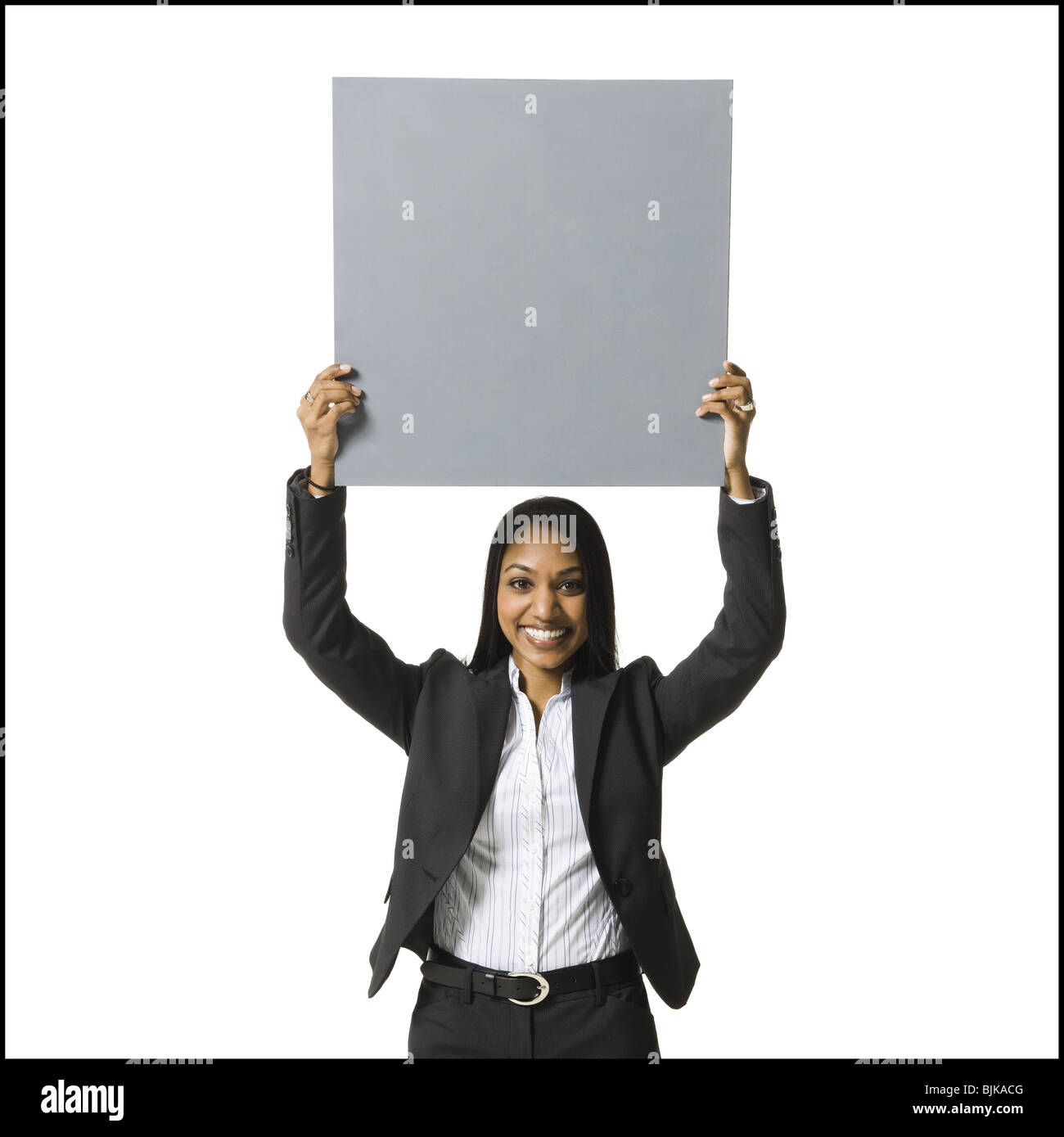 Businesswoman standing with blank sign over head Stock Photo