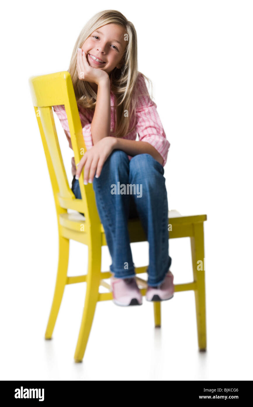 Girl sitting on yellow chair smiling Stock Photo - Alamy
