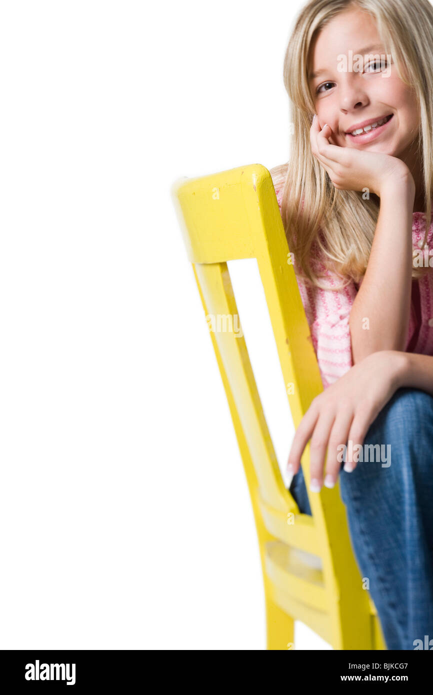 Girl sitting on yellow chair smiling Stock Photo - Alamy