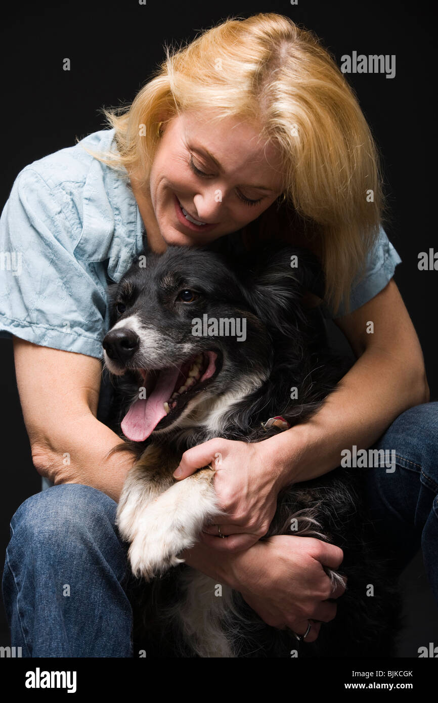 Portrait of a woman facing black dog smiling Stock Photo