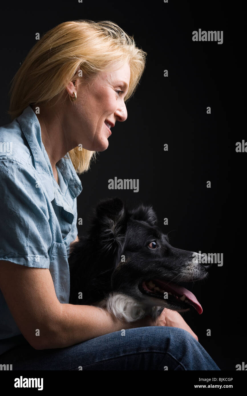 Portrait of a woman facing black dog smiling Stock Photo