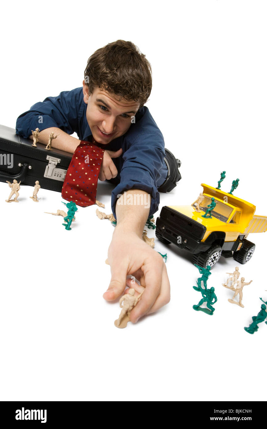 Young businessman playing with plastic army men and truck Stock Photo