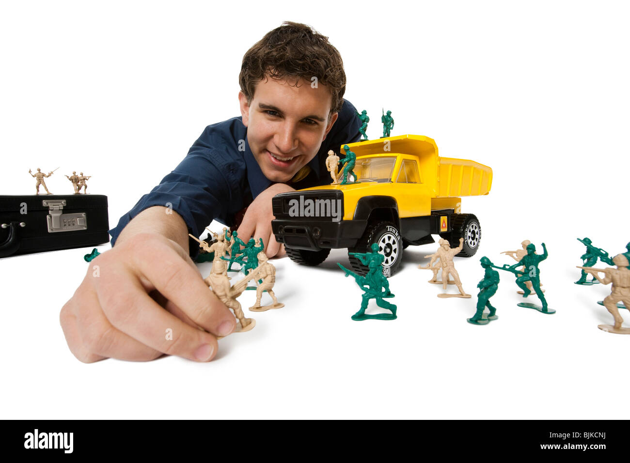 Young businessman playing with plastic army men and truck Stock Photo