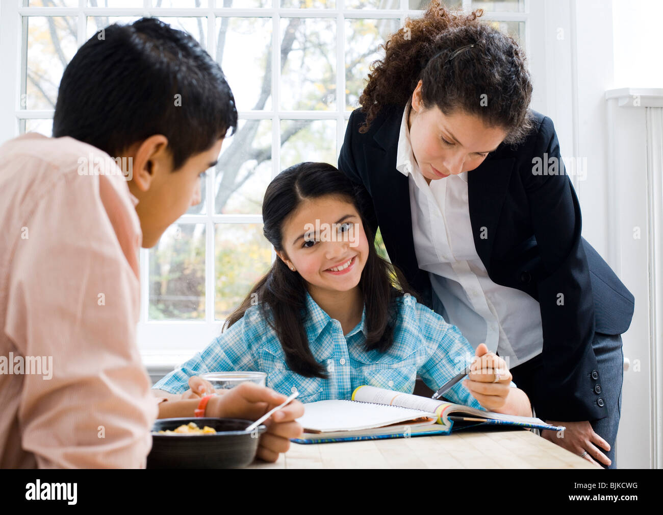 Girl doing homework with woman watching Stock Photo - Alamy