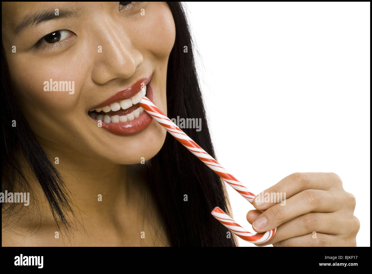 Closeup of woman with red lipstick eating candy cane Stock Photo