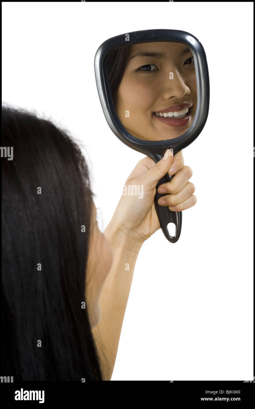 Reflection of woman in hand mirror Stock Photo
