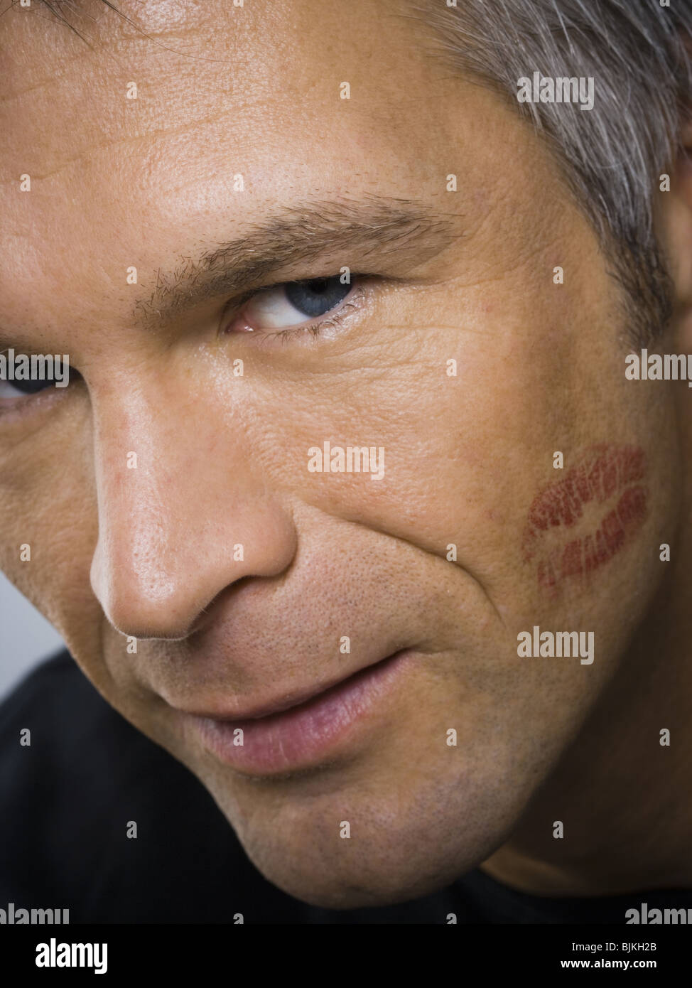 Closeup of mature man with lipstick kiss on cheek Stock Photo