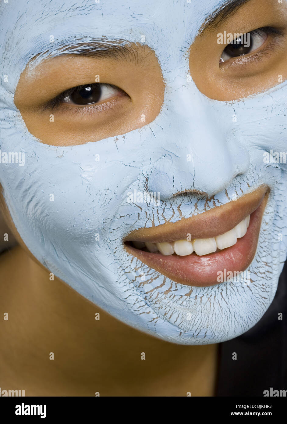 Closeup of woman smiling with facial mask Stock Photo