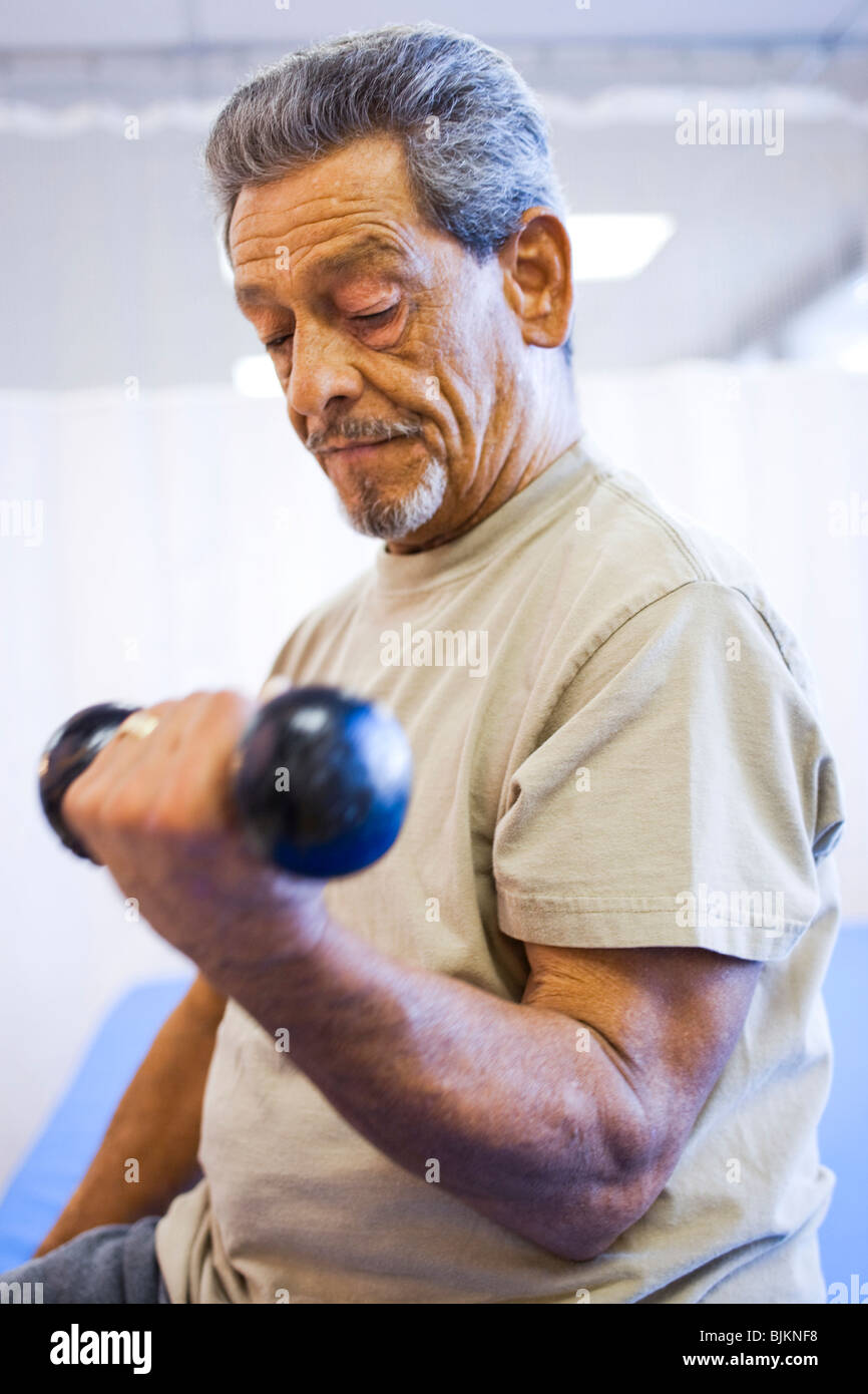 Man with one leg sitting and exercising with weights Stock Photo