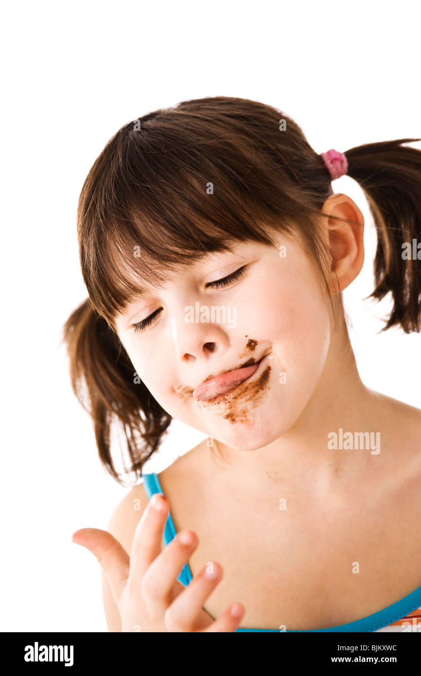 Little girl with pigtails licking chocolate off her finger Stock Photo
