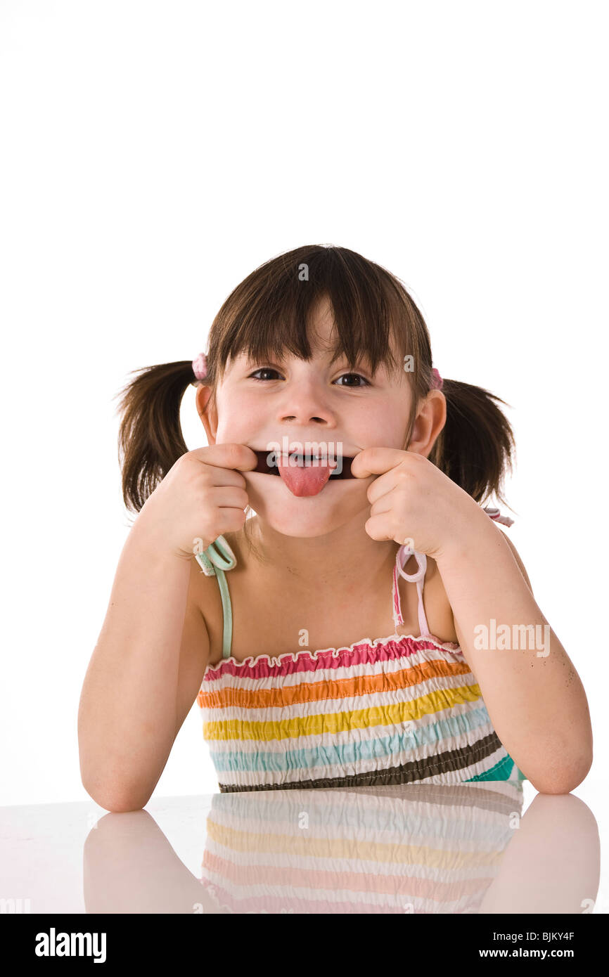 Cheeky girl with pigtails sticking out her tongue Stock Photo