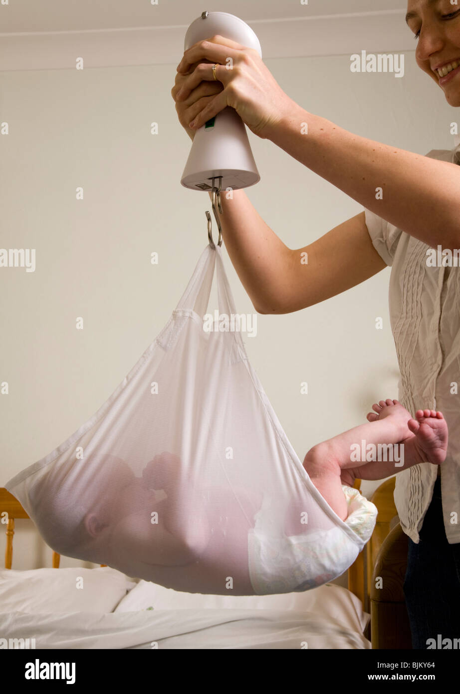 Weighing a newborn / new born baby with scales / weight scale. Stock Photo