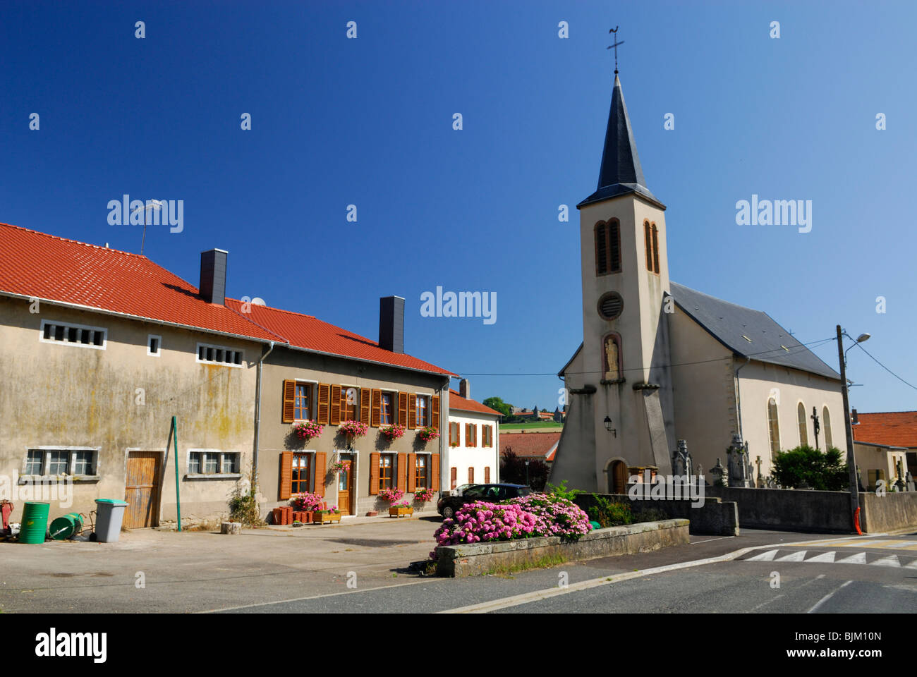Typical french village centre with the catholic church and old houses. Village of Guinglange. Moselle, Lorraine region, France Stock Photo