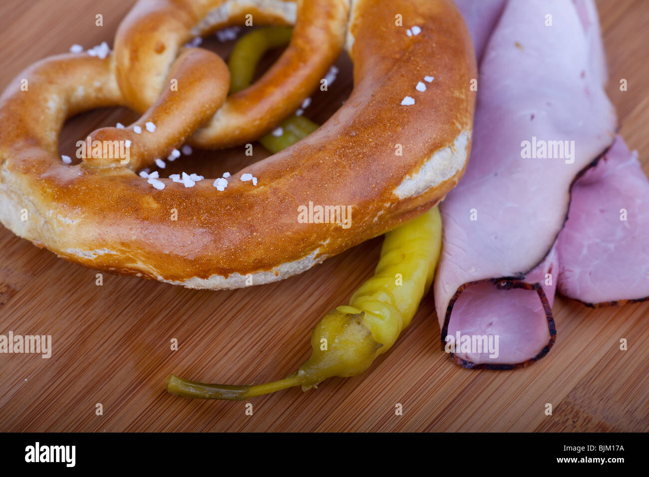 ham, pretzel and a peperoni on a wooden chopping board Stock Photo Alamy
