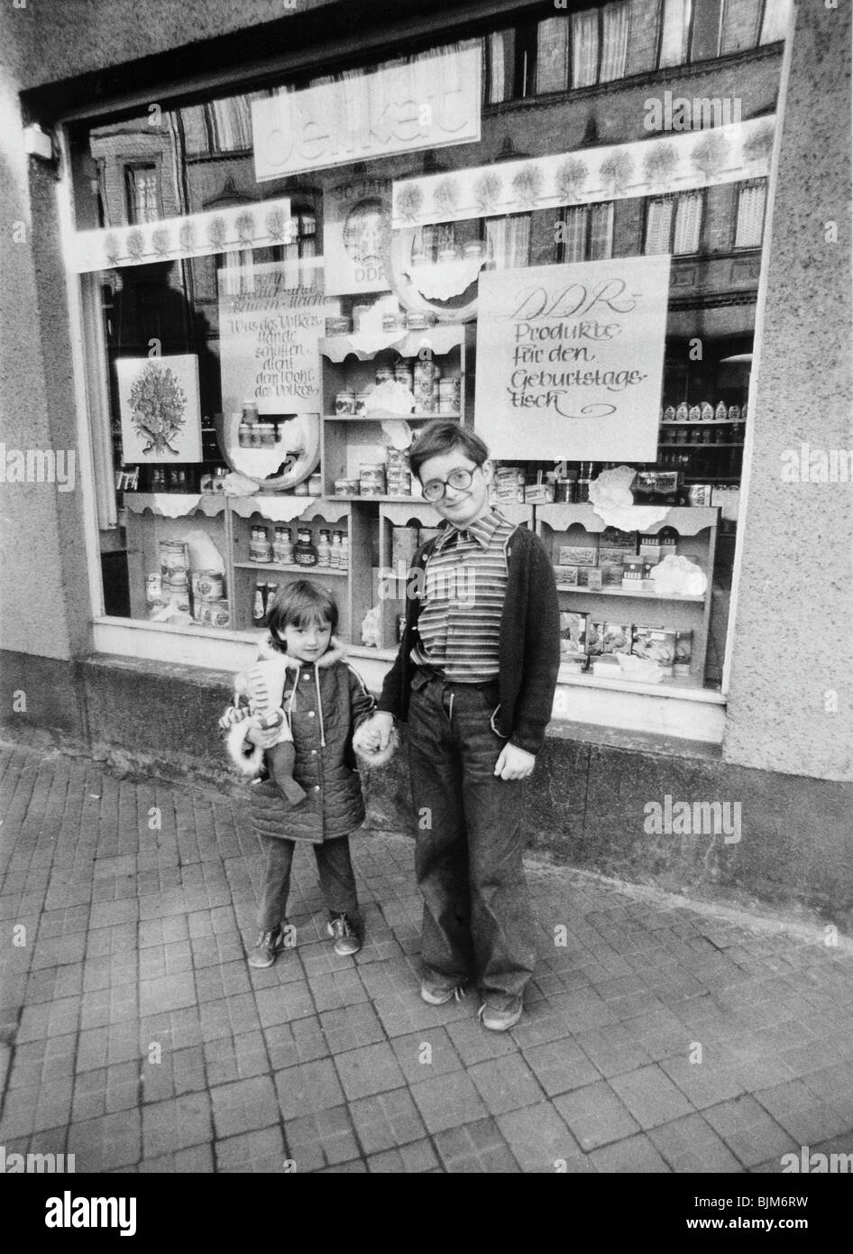 Children in front of a delicatessen with advertising for the anniversary of the Republic, East Germany, Germany, Europe, circa  Stock Photo