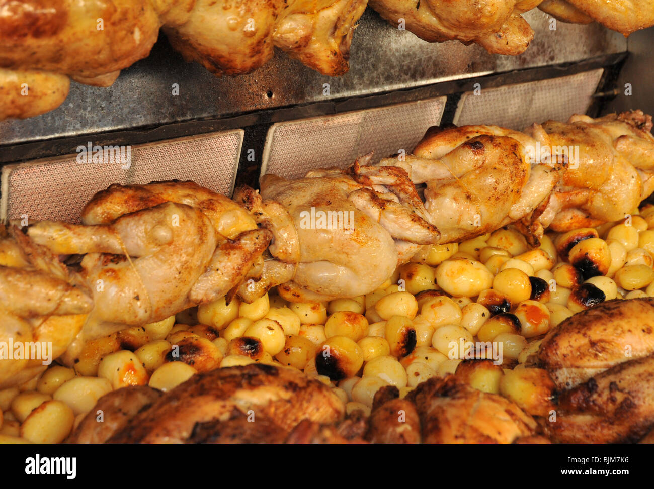 A commercial large scale whole chicken and roast potato rotisserie