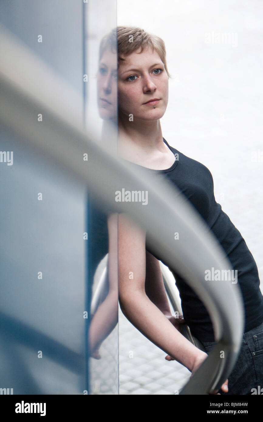 Young woman, portrait against a railing with a reflection in glass Stock Photo