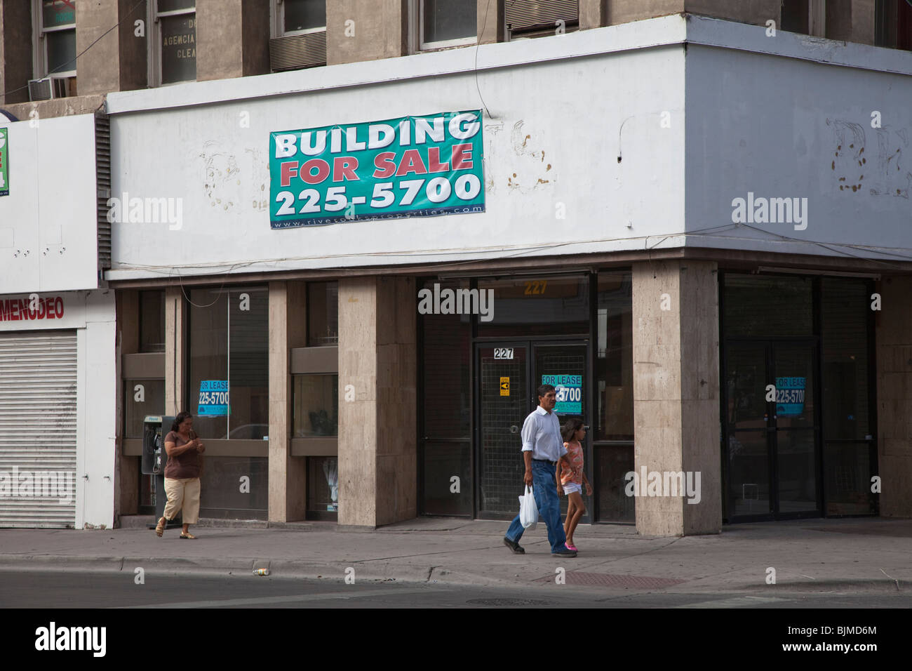 People walking past building for sale with closed shop El Paso Texas
