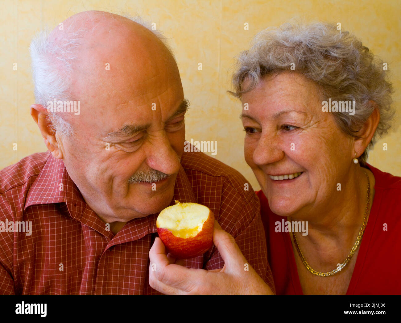 Woman feeding a man an apple, pensioners Stock Photo