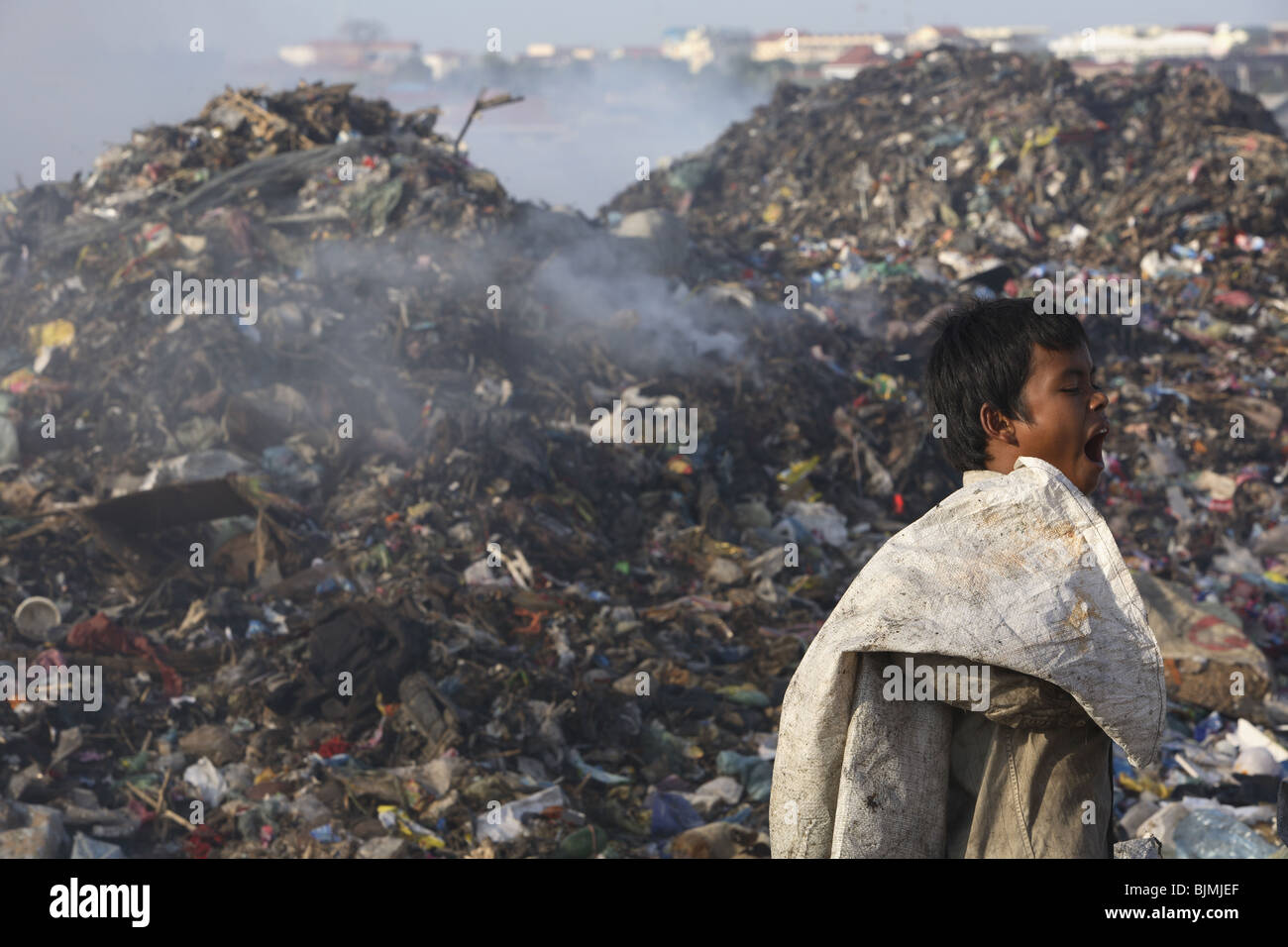 A young boy yawns while working on a garbage dump in Phnom Penh, Cambodia. Stock Photo