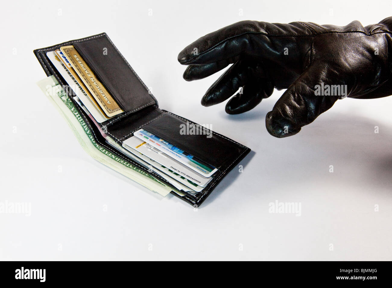 Thief, fraudster, glove reaching for a wallet with cash and credit cards Stock Photo