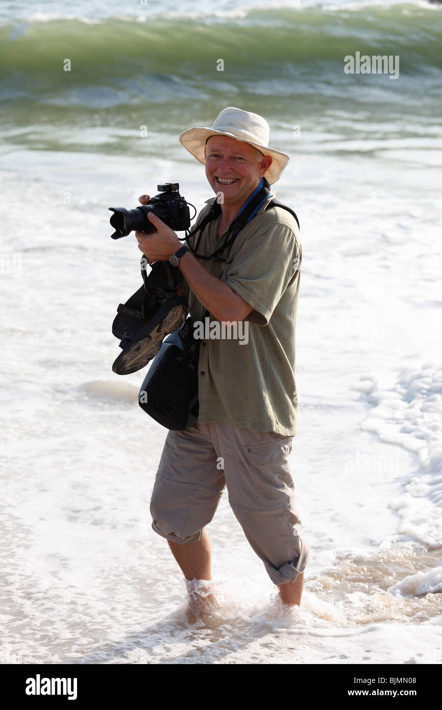 Photographer with camera in the water on the beach, Malabarian Coast, Malabar, Kerala state, India, Asia Stock Photo
