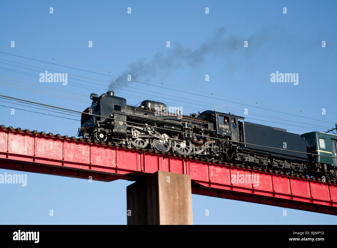 Steam train crossing railway bridge Stock Photo
